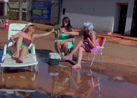 Amigas simulam praia em protesto contra buracos em rua>
